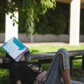 Burnout scolastico: in primo piano una ragazza con un libro sulla faccia.