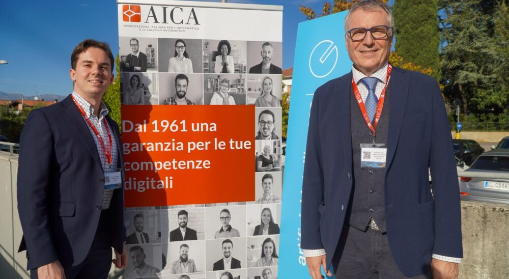 Roberto Ronutti, direttore del Centro Studi Excol, davanti al roll-up AICA al Congresso AICA 2026 a Tavagnacco